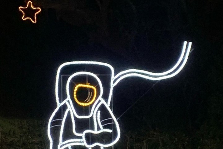 Neon outline of an astronaut floating with a star in the background.