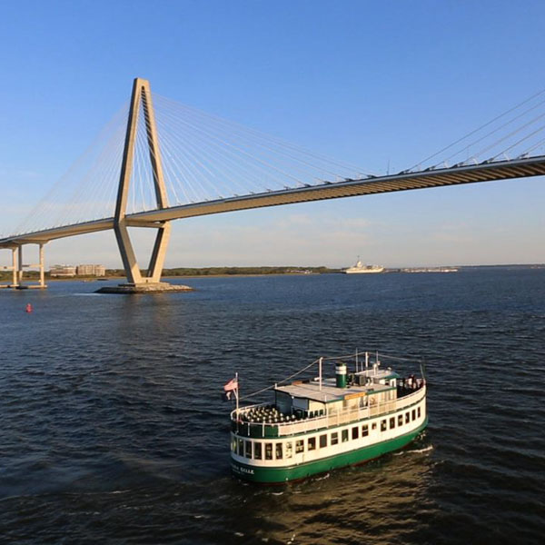 Boat on water under a cable-stayed bridge during a clear day.